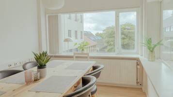 A modern dining area with a wooden table, chairs, and a view of the outside.