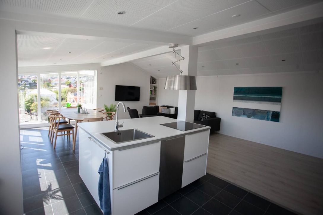 Una cocina moderna con una isla central, una zona de comedor con sillas y un amplio ventanal con vistas al exterior.
