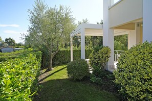 A well-maintained garden with a white pergola structure, surrounded by various shrubs and trees. - Villetta I Giardini del Garda (Peschiera del Garda)