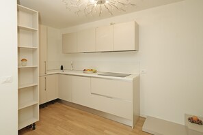 A compact kitchen with white cabinetry, a wooden floor, and a ceiling light fixture. - Villetta I Giardini del Garda (Peschiera del Garda)