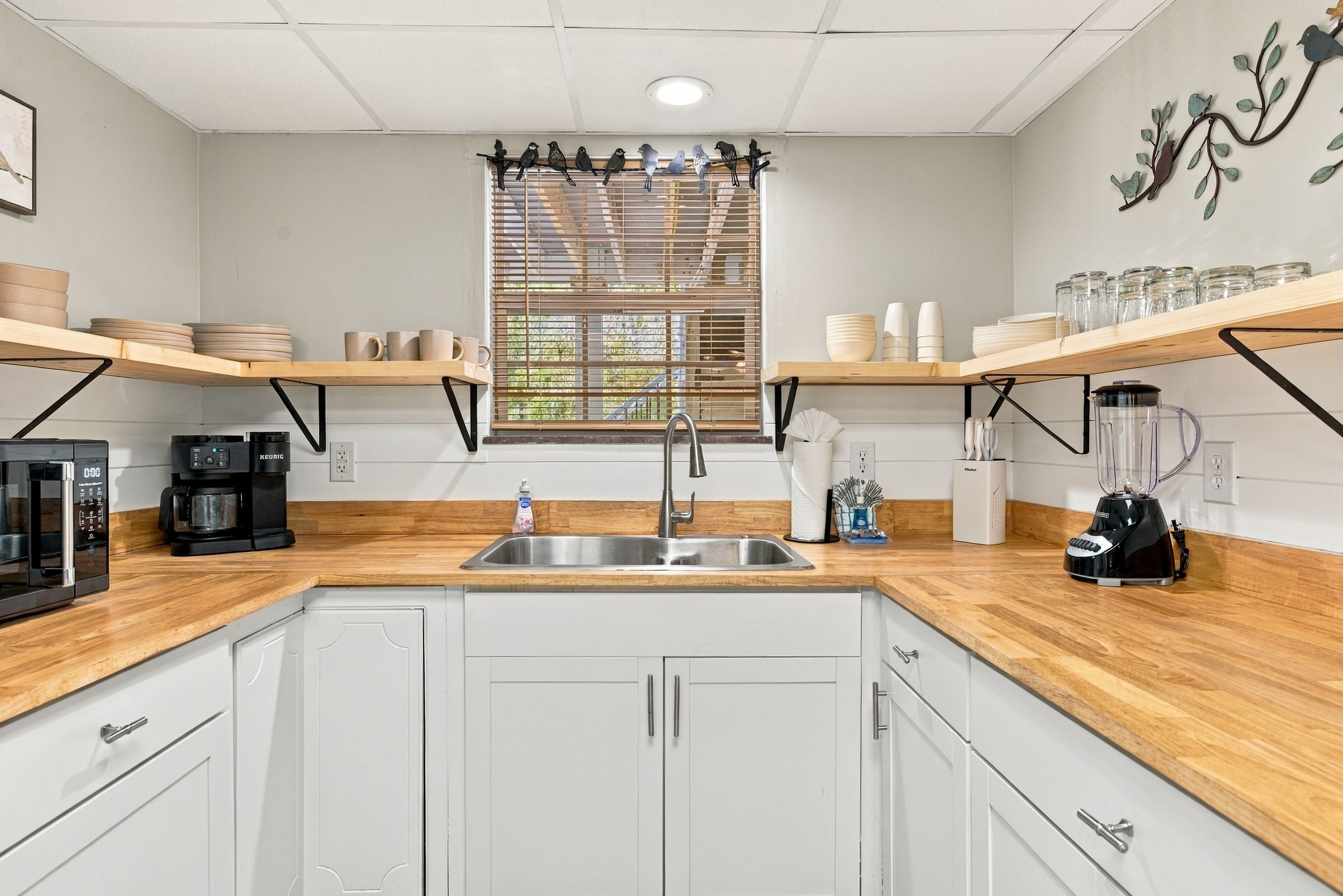 A modern kitchen with white cabinets, a stainless steel sink, and wooden countertops.