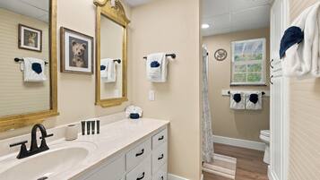 A bathroom with a large mirror, a sink, and a shower.