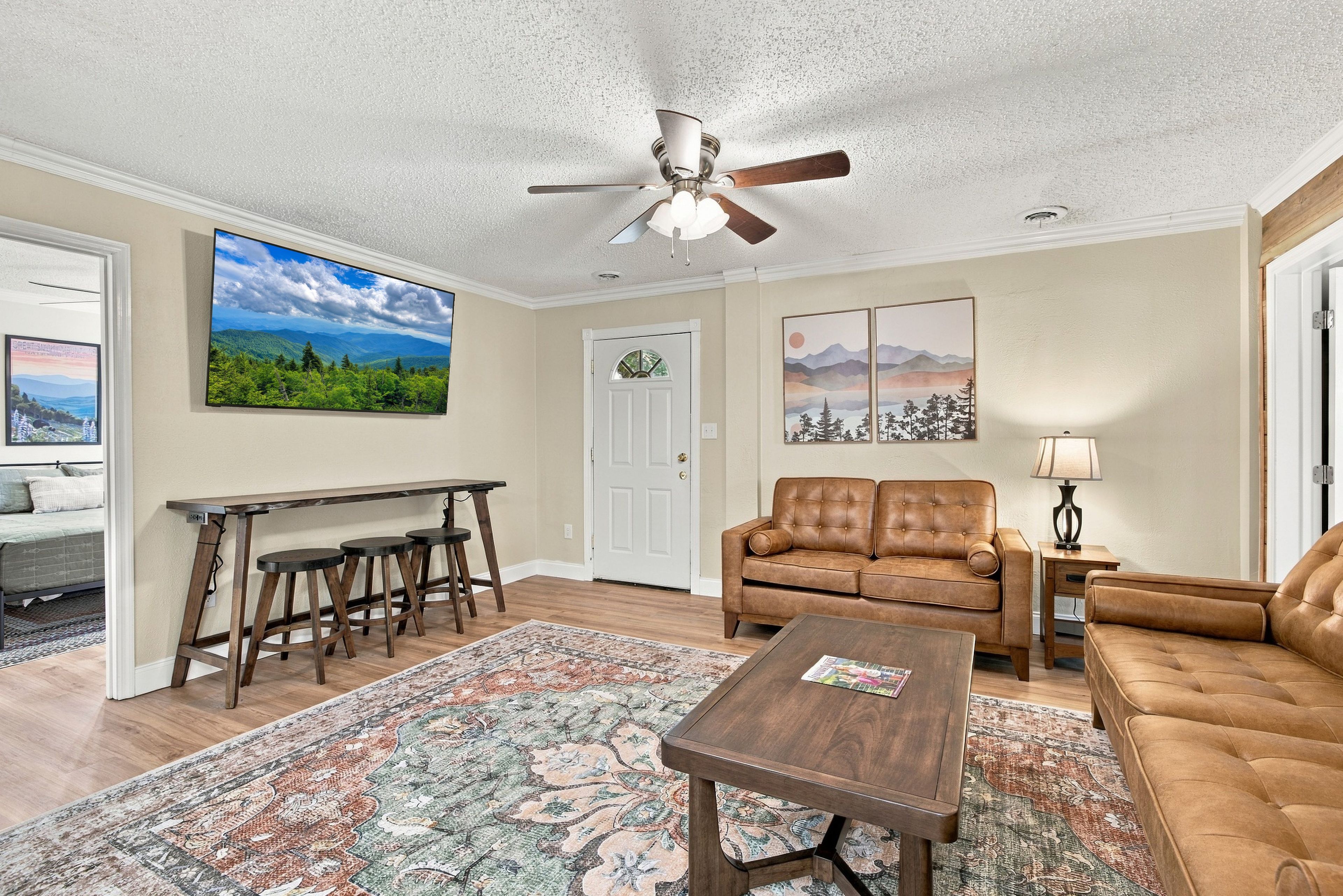 A living room with a ceiling fan, a sofa, a coffee table, a rug, and artwork on the walls.