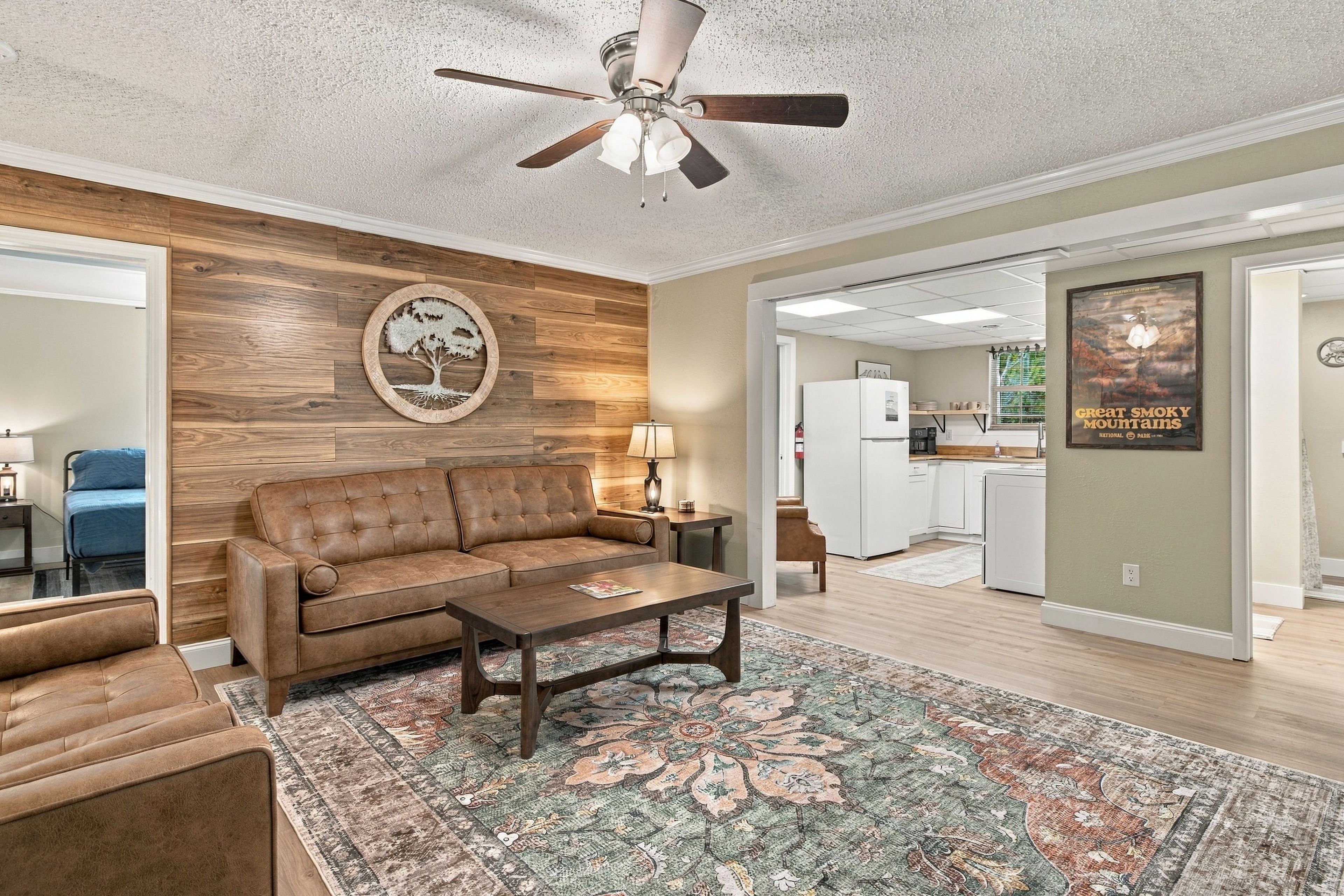 A living room with a brown leather sofa, a coffee table, and a patterned rug.