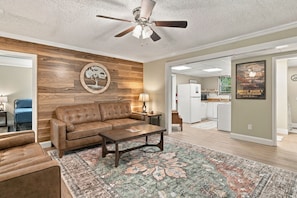 A living room with a brown leather sofa, a coffee table, and a patterned rug.