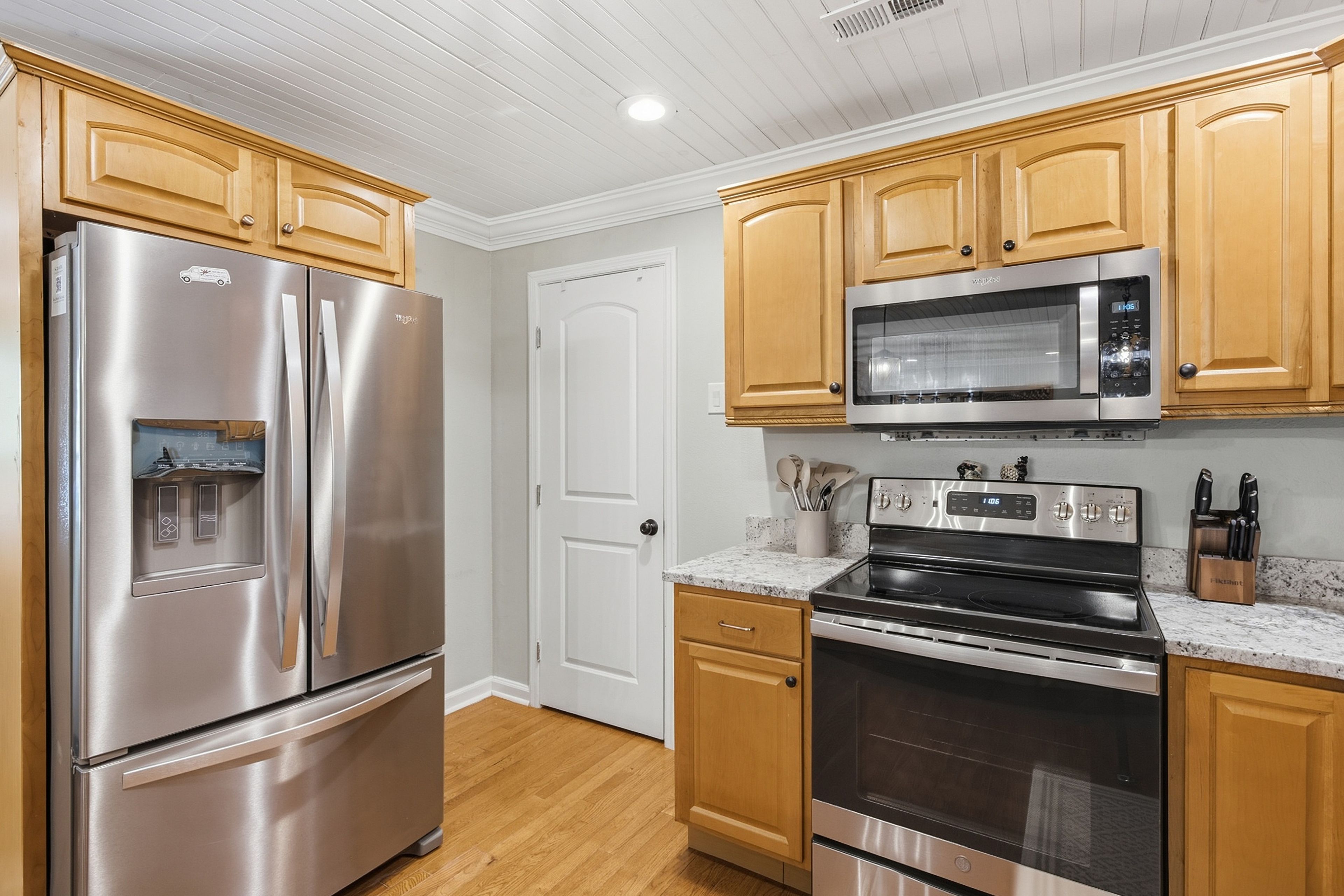 A kitchen with stainless steel appliances, wooden cabinets, and a granite countertop.