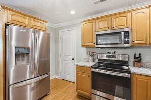 A kitchen with stainless steel appliances, wooden cabinets, and a granite countertop.