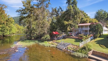 A riverside property with a house, a gazebo, and a clear view of the river.