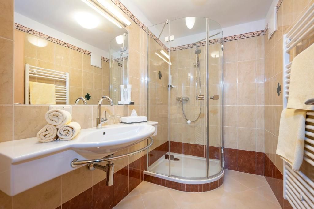 A modern bathroom with a glass-enclosed shower, a sink with a vanity, and a towel rack.