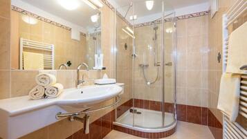 A modern bathroom with a glass-enclosed shower, a sink with a vanity, and a towel rack.