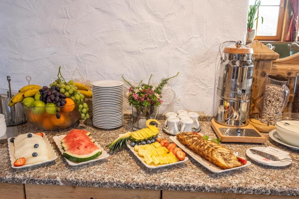 Ein reichhaltiges Frühstücksbuffet mit verschiedenen Früchten, Backwaren und einer Kaffeestation.