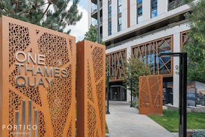 Ein moderner Gebäudeeingang mit einem Schild, auf dem 'ONE THAMES QUAY' steht, und dem Logo 'PORTICO RESIDENCES'.