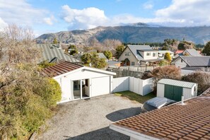 A residential area with houses, a fenced yard, and mountains in the background. - Apollo Hideaway | Self-Contained 1-Bedroom Retreat, Full Kitchen & Easy Access to Wānaka (Wānaka)