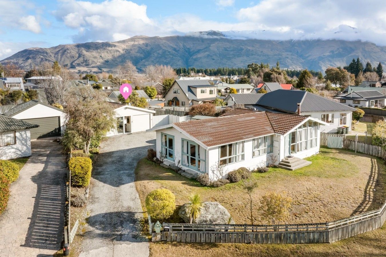 A residential area with houses, a driveway, and a mountain backdrop.
