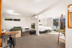 A hotel room with a bed, a sofa, a dining table, and a balcony. - Apollo Hideaway | Self-Contained 1-Bedroom Retreat, Full Kitchen & Easy Access to Wānaka (Wānaka)