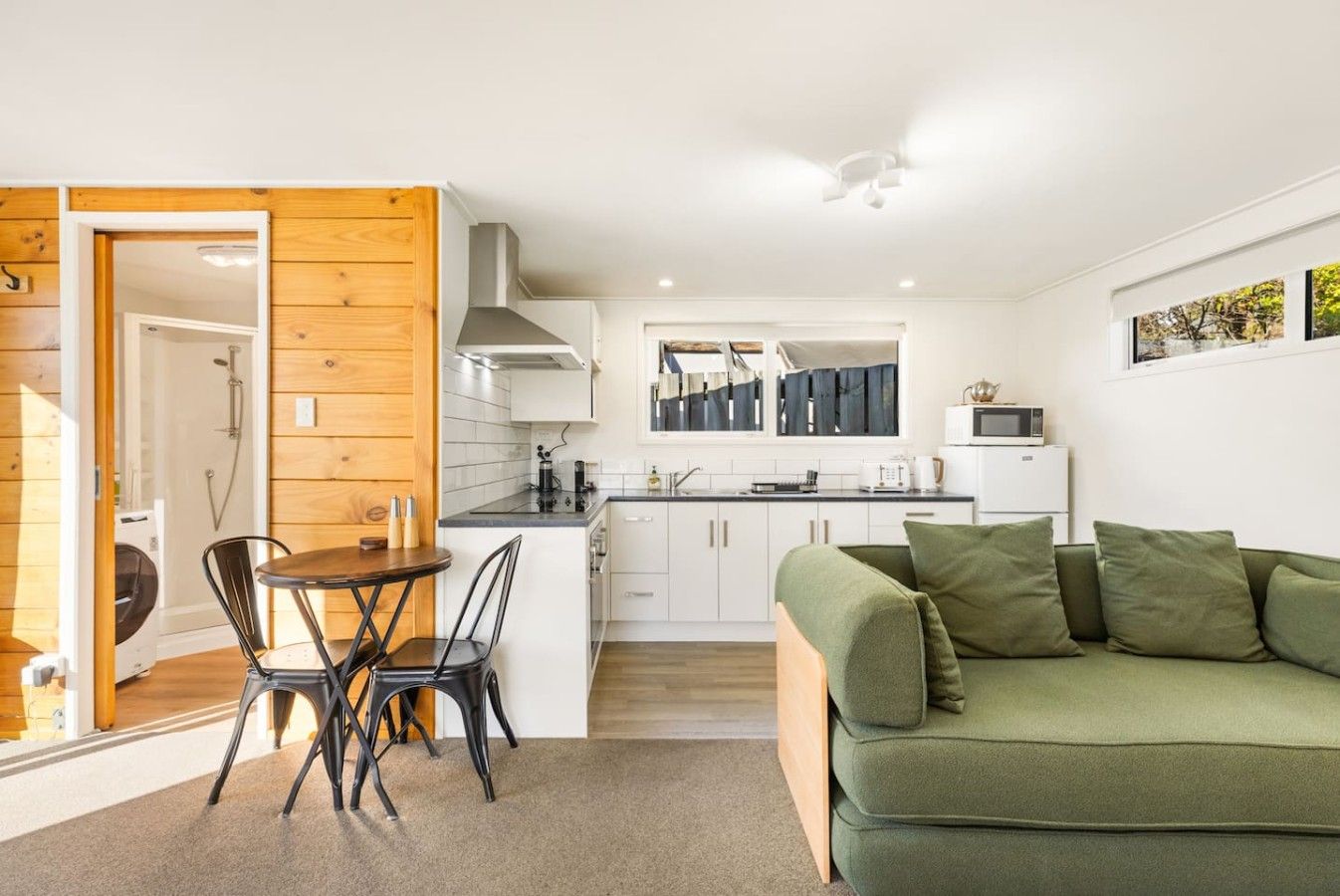 A modern interior with a dining area, kitchen, and a green sofa.