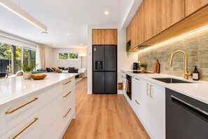 A modern kitchen with a black refrigerator, white cabinetry, and a wooden countertop. - Modern Wānaka Retreat | 4 Bedrooms, Sleeps 8, Hot Tub, 2 Living Areas & Balcony (Wānaka)