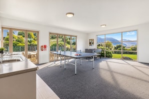 A modern kitchen with a sink and a dining area with a table and chairs. - our Wānaka Base | Sleeps 6, 3 Bedrooms, Mountain Views, Pool, Spa, Gym & Tennis Court (Wānaka)