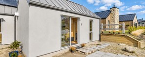 Ein modernes Gebäude mit einer großen Glasdoor, einem Steinkamin und einer Holzdachterrasse.