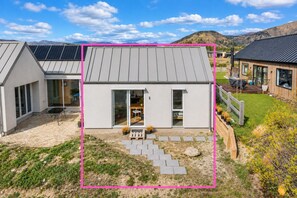 A modern house with a flat roof, large windows, and a patio area with outdoor furniture.
