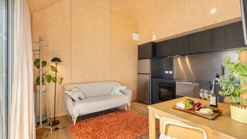 A modern kitchen with a built-in oven, a dining table with a chair, and a sofa with cushions.
