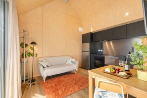 A modern kitchen with a built-in oven, a dining table with a chair, and a sofa with cushions.