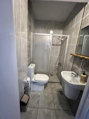 Pieni kylpyhuone, jossa on wc, suihku ja pesuallas.