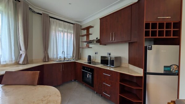 A compact kitchen with wooden cabinets, a built-in microwave, and a refrigerator.