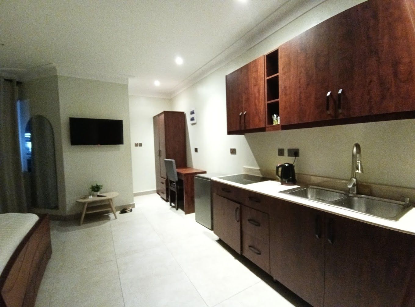 Cocina compacta con armarios de madera, un lavamanos integrado y un pequeño comedor.