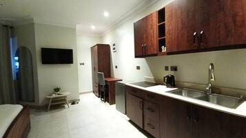 Cocina compacta con armarios de madera, un lavamanos integrado y un pequeño comedor.