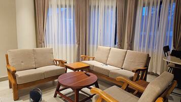 A living room with a sofa set, a coffee table, and a small table with chairs.