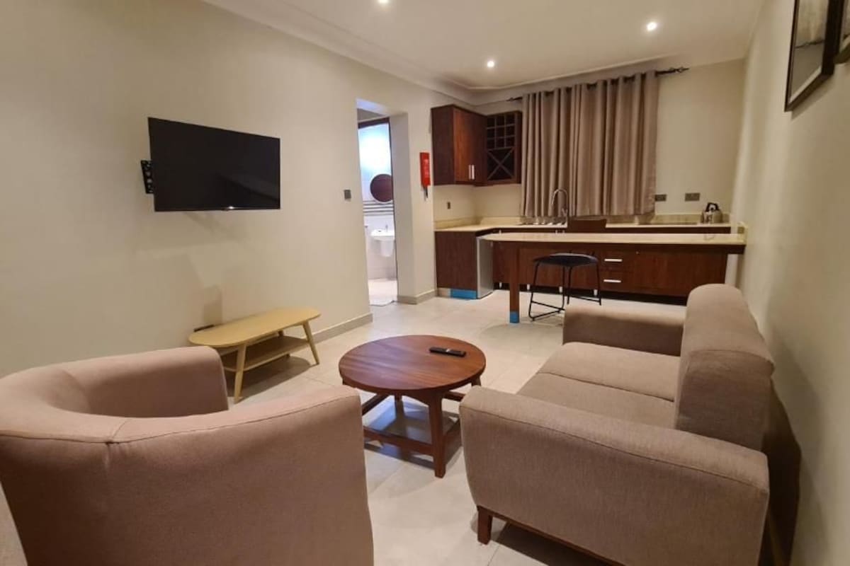 A living room with a sofa, a coffee table, and a TV mounted on the wall.