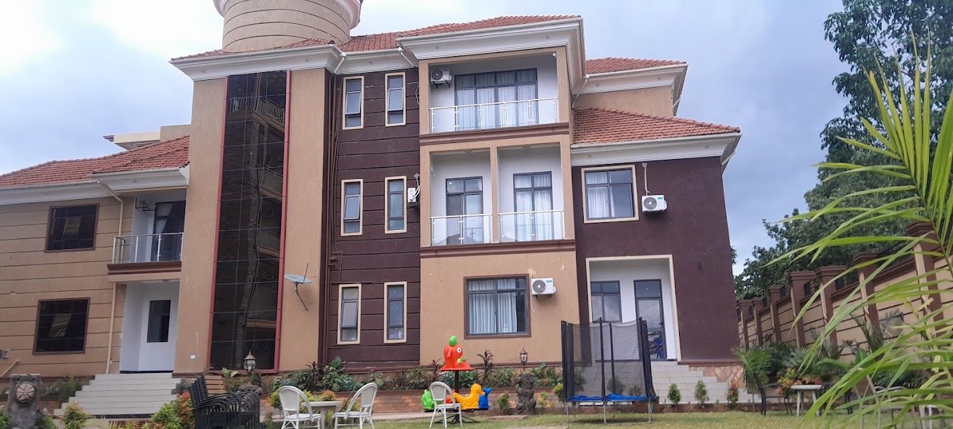 Un edificio residencial de varios pisos con balcones, unidades de aire acondicionado y una pequeña zona de estar al aire libre con sillas y una mesa.
