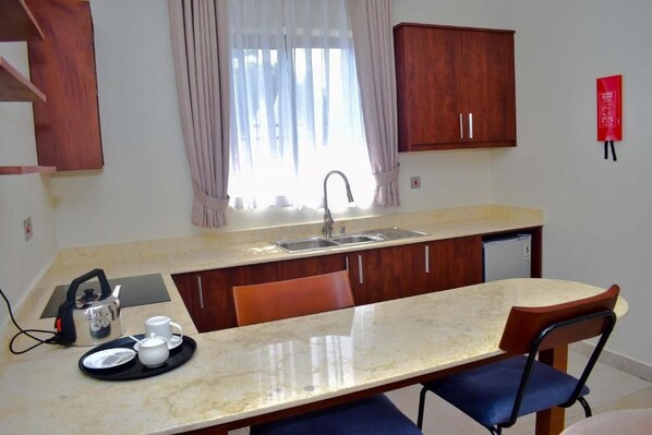 A compact kitchen with a sink, a kettle, and a breakfast tray.