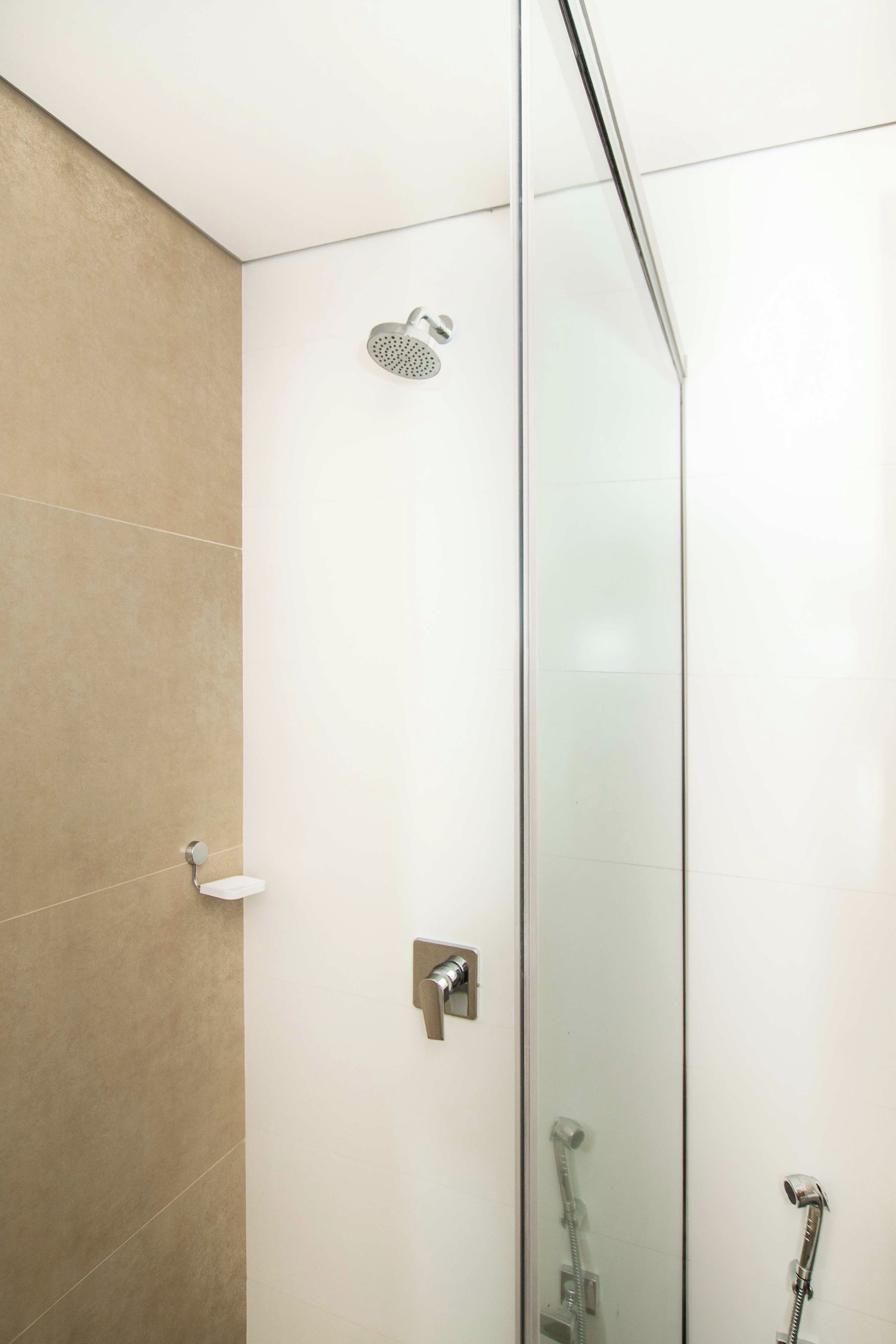 Un baño moderno con cabina de ducha de vidrio, ducha de mano y grifo empotrado.