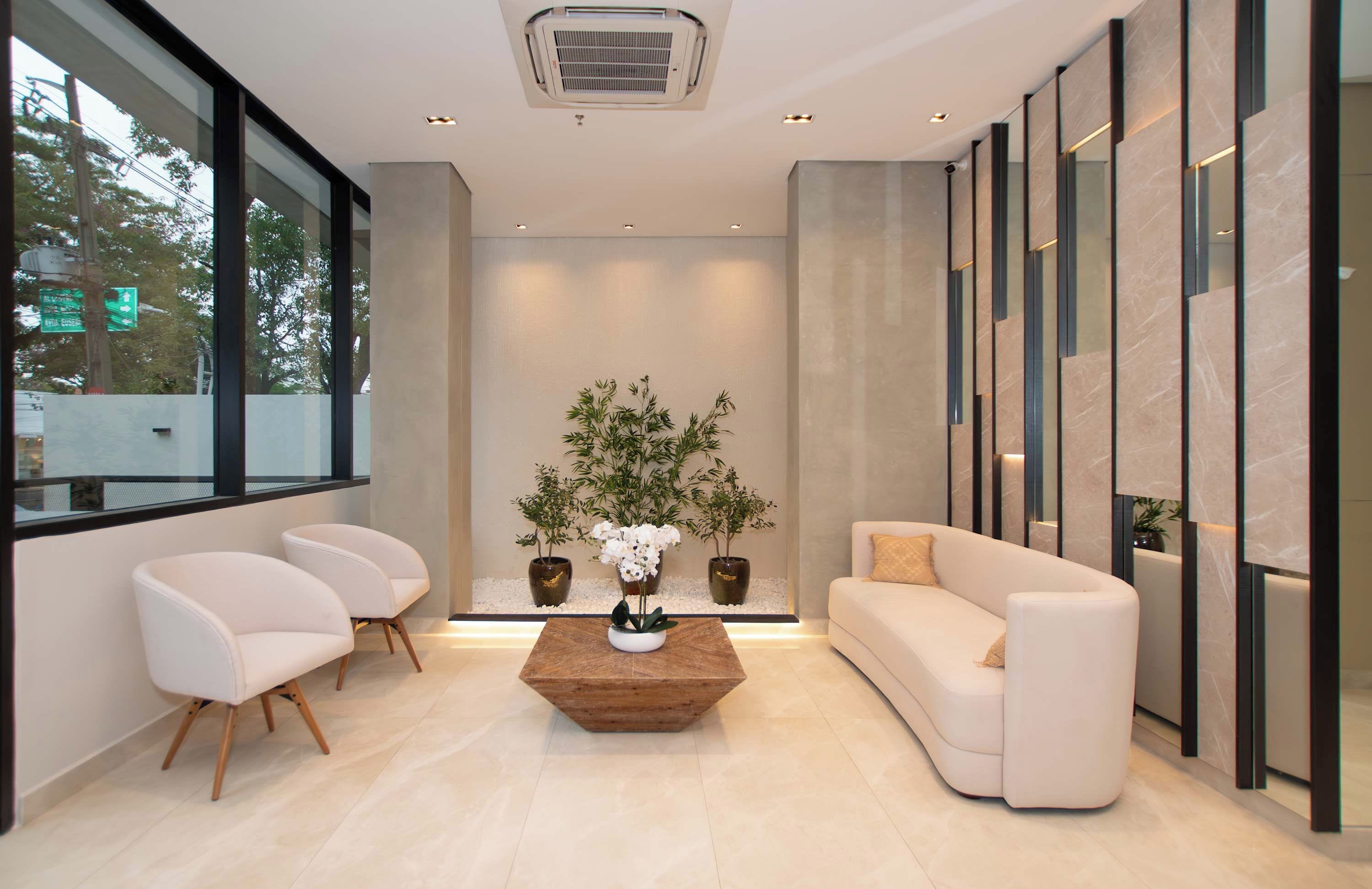 Um interior moderno com sofá, cadeiras, mesa de centro e plantas em vasos.