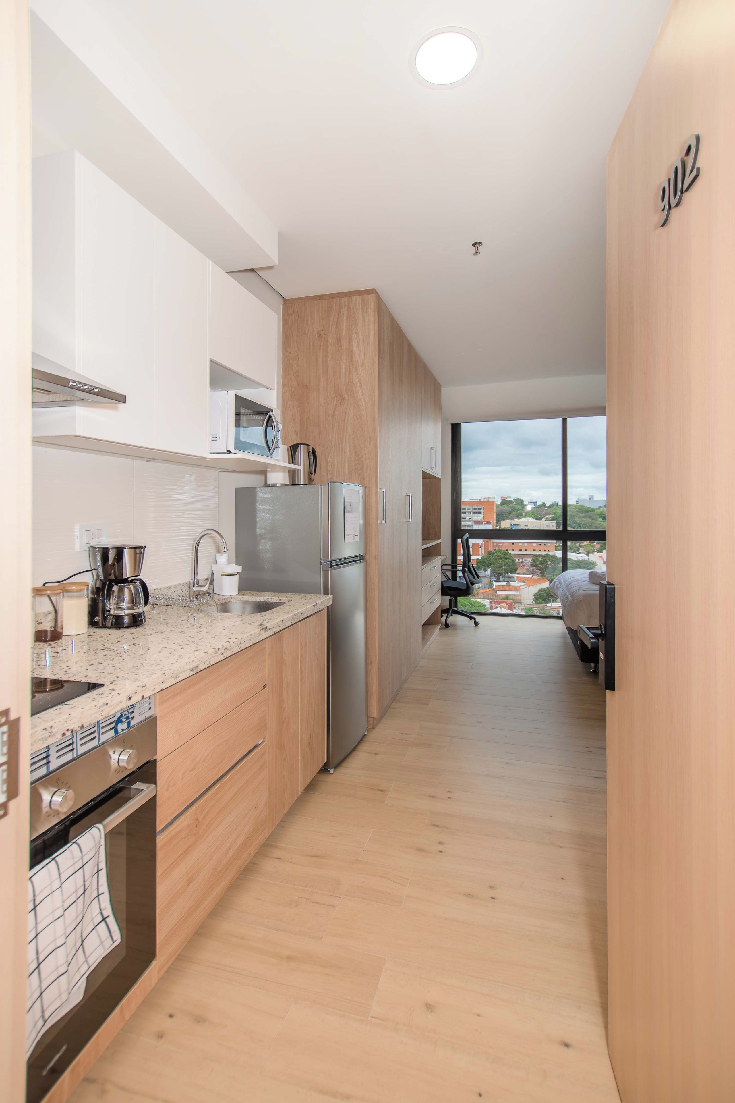 Una cocina moderna con un refrigerador de acero inoxidable, un microondas y una cafetera.