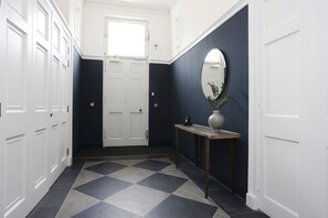 A hallway with a checkered floor, a white door, a dark wall, and a round mirror. - Elegant Studio by Royal Mile, Walk to Edinburgh (Edinburgh)