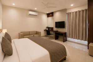 A hotel room with a bed, a desk, a chair, a TV, an air conditioner, and a window with curtains. - Hotel Element Stay By OTABoostup  (Hyderabad)