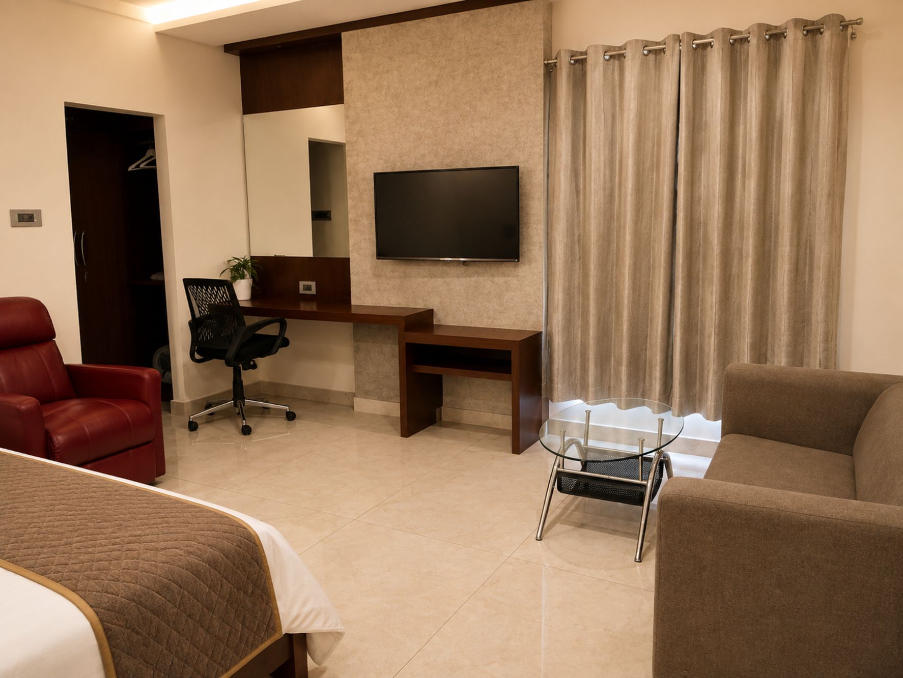 A hotel room with a bed, a desk, a chair, a TV, and a sofa.