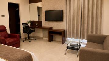 Una habitación de hotel con cama, escritorio, silla, televisor y sofá.