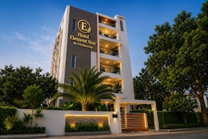 A multi-story hotel building with a prominent logo, balconies, and a well-maintained garden. - Hotel Element Stay By OTABoostup  (Hyderabad)