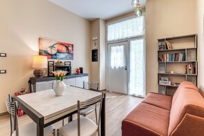 A modern living room with a dining table, sofa, and bookshelf. - Three-room apartment near the Metro station for the Colosseum (Roma)