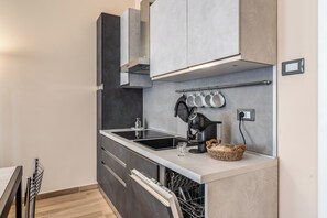 A modern kitchen with a built-in dishwasher, a coffee machine, and a hanging pot rack. - Three-room apartment near the Metro station for the Colosseum (Roma)