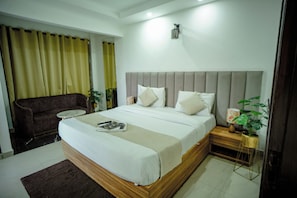 Una habitación de hotel con una cama, una mesita de noche, una silla y una planta en maceta.