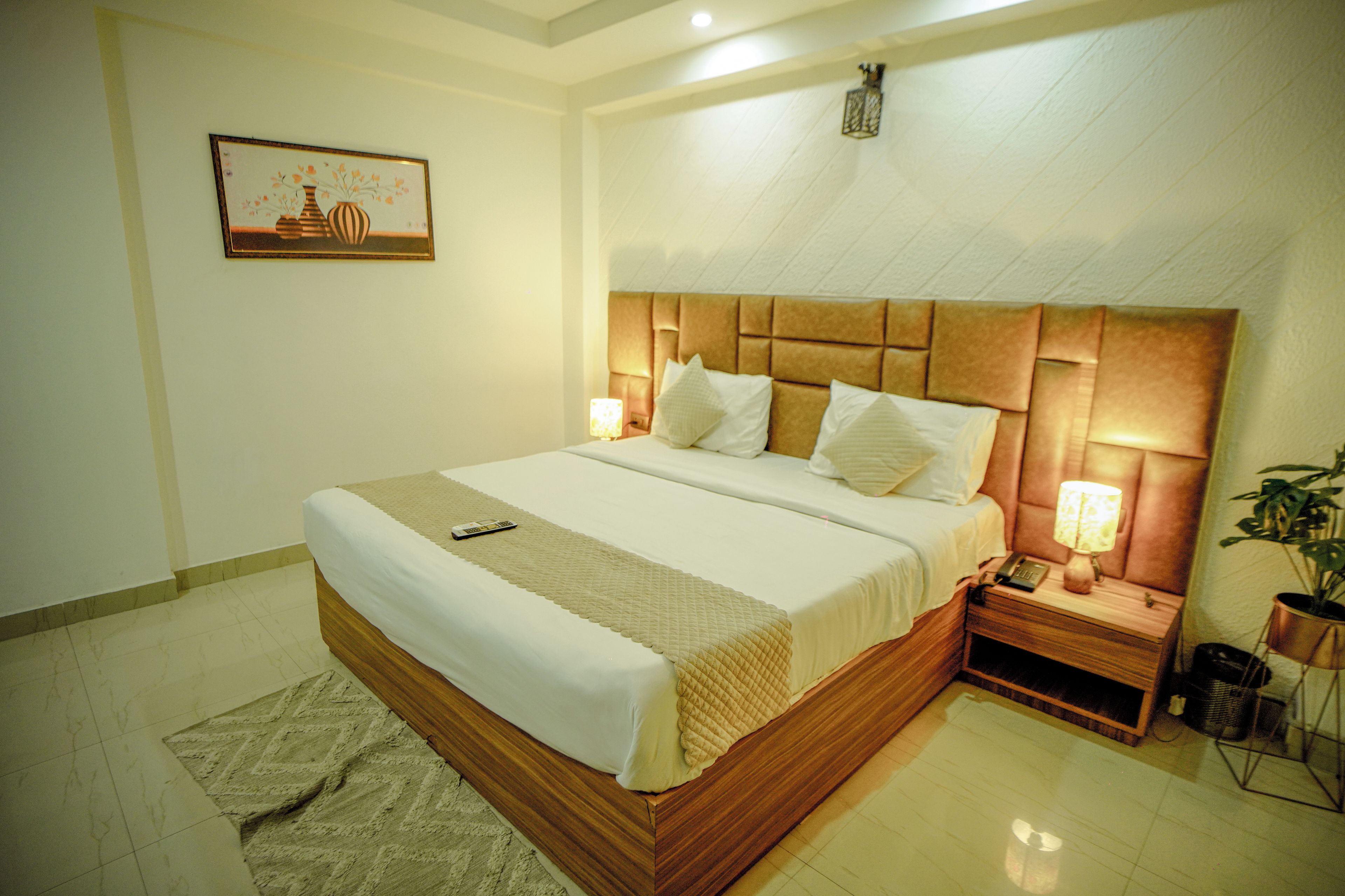 Quarto de hotel com uma cama grande, luminárias de cabeceira, mesa de cabeceira e um quadro na parede.