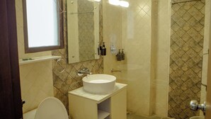 A bathroom with a toilet, sink, and shower. - Hotel Trisha (Gurugram)