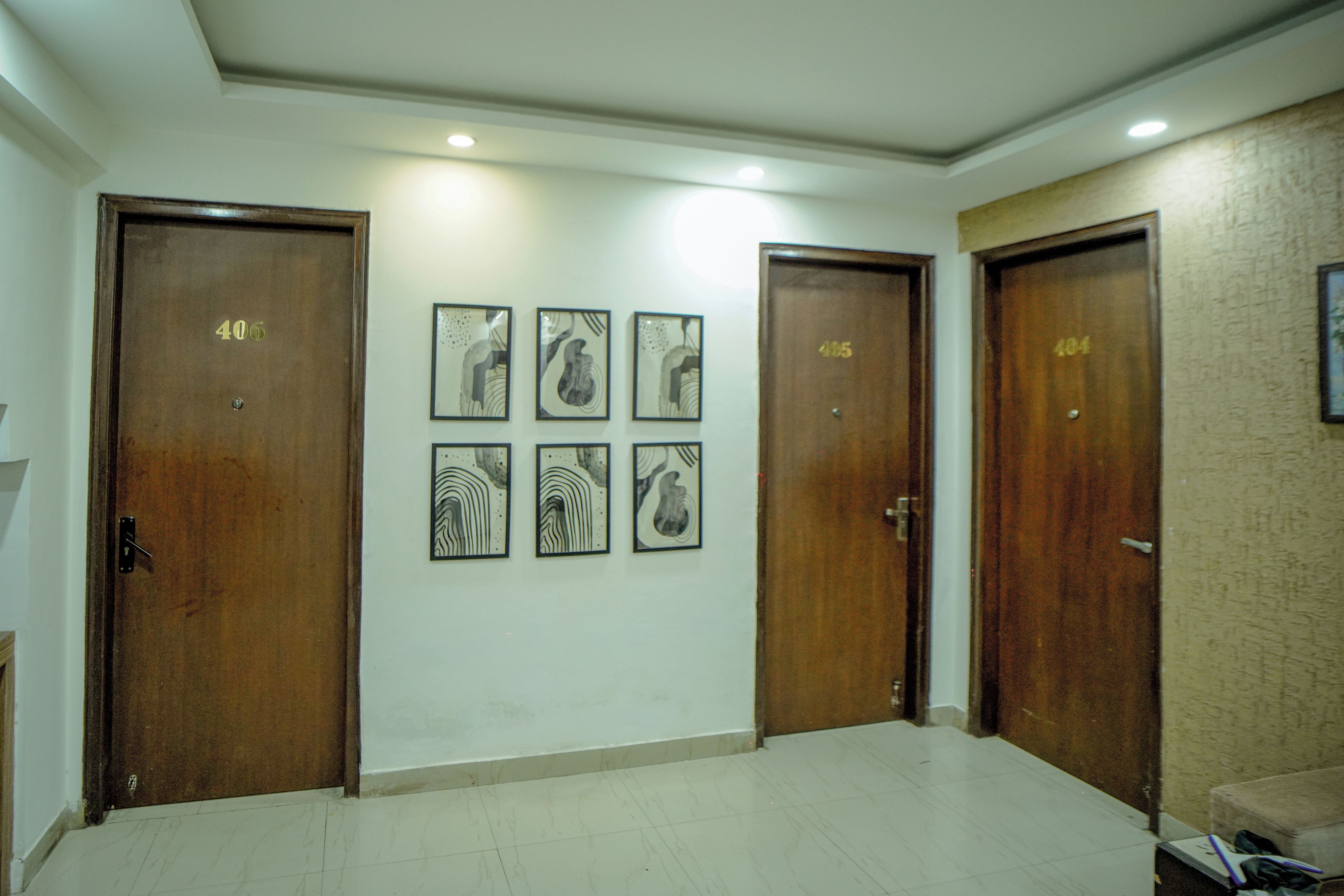 Un pasillo con cuatro puertas de madera, cada una con un número. Seis obras de arte enmarcadas adornan la pared.