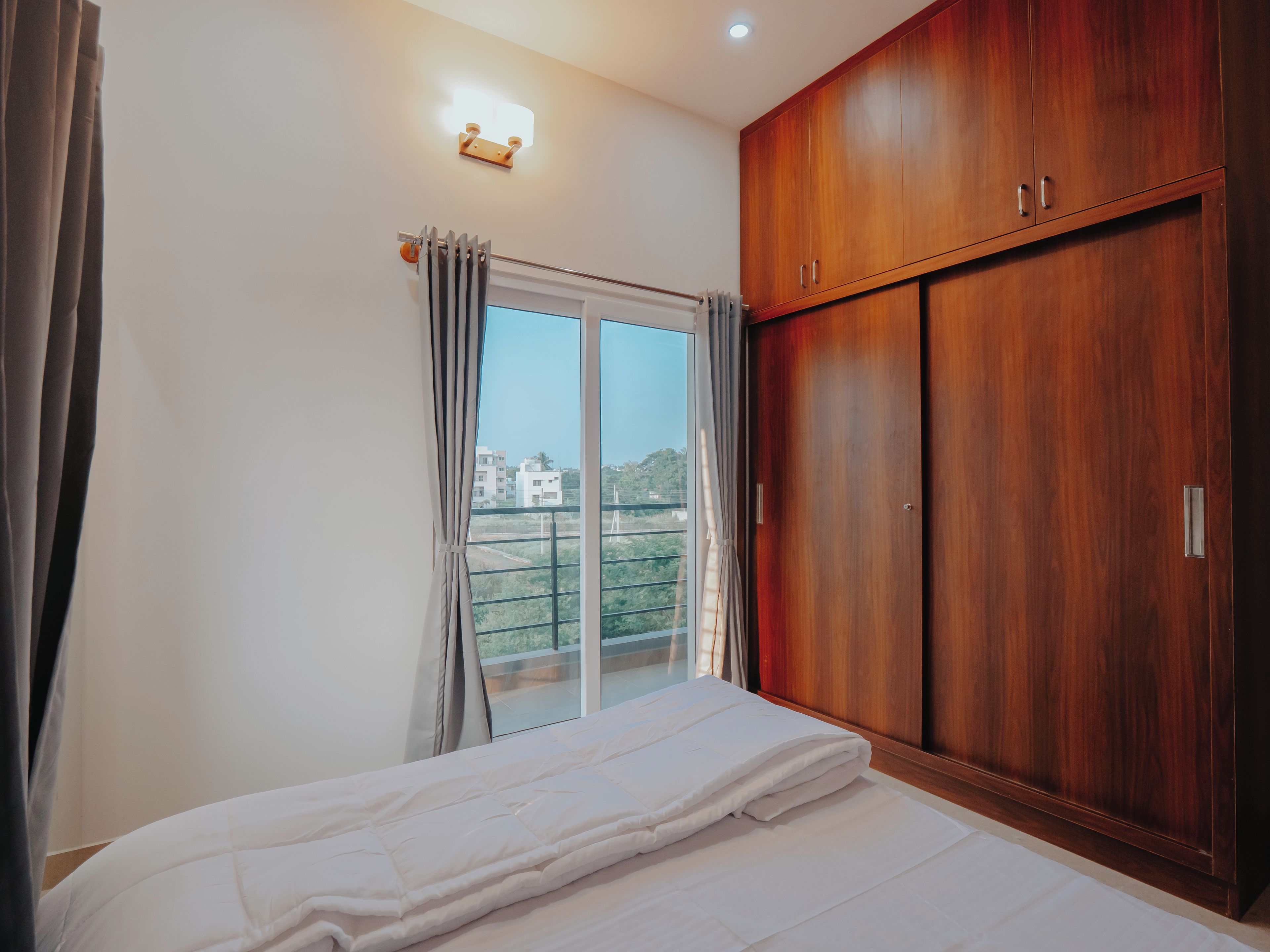 Een slaapkamer met een groot raam, een kledingkast en een bed.