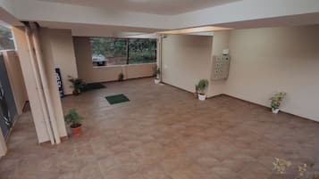 A spacious indoor area with tiled flooring, potted plants, and a view through a glass door.